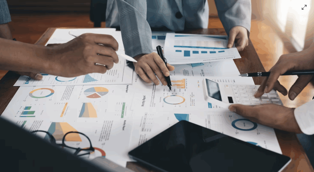 People at a conference room table reviewing charts and graphs.