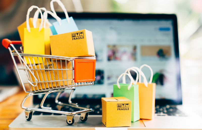 Shopping cart filled with items next to computer. Showing relationship between AI and shopping